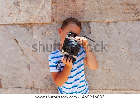 cute boy is making photographs against the stone wall