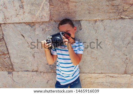 cute boy is making photographs against the stone wall