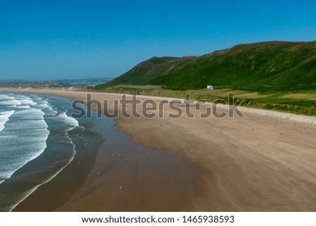 A huge golden sandy beach with breaking surf and green hills