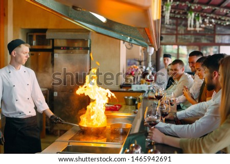 The chef prepares food in front of the visitors in the restaurant.