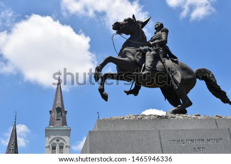 Jackson Square New Orleans Louisiana Statue of Andrew Jackson on horse with with St. Louis Cathedral’s steeples and bright blue sky with clouds in background Royalty-Free Stock Photo #1465946336