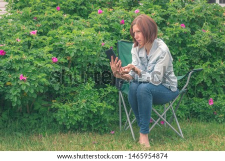 Young thoughtful red-haired woman on vacation with portable tablet. Enjoying weekend vacation. Woman browses social networks and search engines. Technologies leisure and lifestyle concept