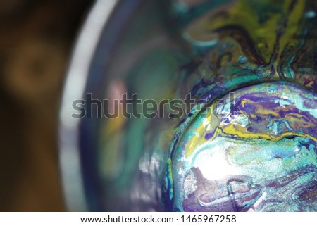 Cup with wet textured paint after acrylic paint pouring technique with shiny metallic colors. Aqua blue, purples, pinks, and lime greens. Colorful abstract background. Royalty-Free Stock Photo #1465967258