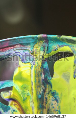 Cup with wet textured paint after acrylic paint pouring technique with shiny metallic colors. Aqua blue and lime greens. Colorful abstract background. Royalty-Free Stock Photo #1465968137