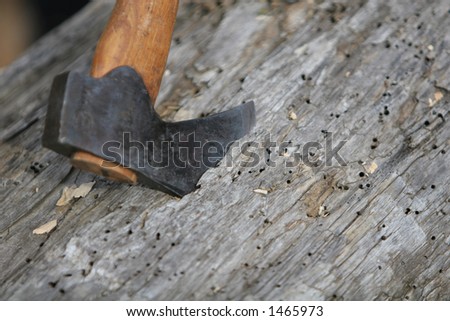 An axe buried into a piece of lumber, waiting to be carved into shape by carpenter Royalty-Free Stock Photo #1465973