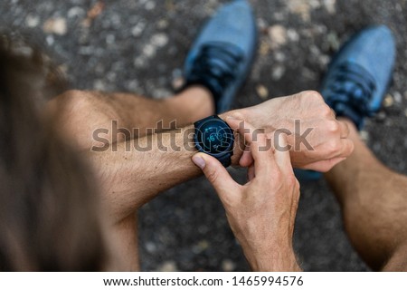 Fit man checking smart watch wearable technology sport smartwatch on fitness run walk outside. Top view from above with running shoes in street. Royalty-Free Stock Photo #1465994576
