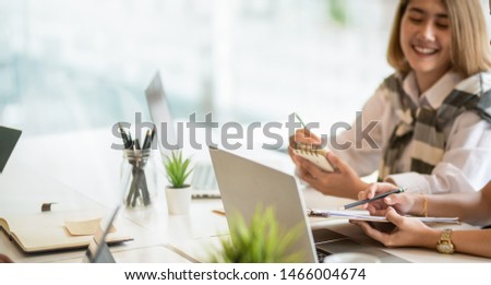 Female freelancer picking up new ideas from her coworkers and writing it on notebook  