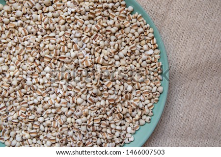 Picture of millet or job’s tears in a green dish that is grains and food on a brown tablecloth, wood grain, suitable for food advertising,top viwe