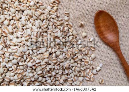 Picture of millet in a wooden spoon that is cereal and food on a brown tablecloth, wood grain, suitable for food advertising,top viwe