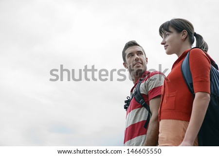 Low angle view of a young couple with backpacks against the sky