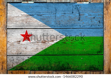 National flag of Djibouti on a wooden wall background.The concept of national pride and symbol of the country.Flag painted on a wooden fence with metal nails.