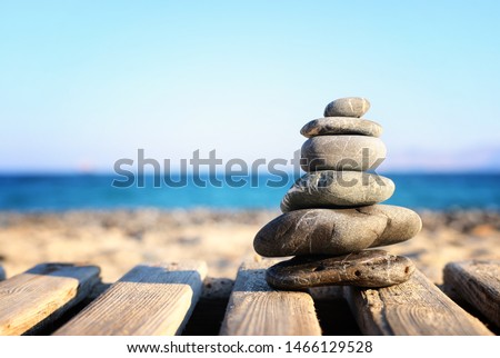 nature image of stones pyramid on over beach wooden deck symbolizing harmony, zen and balance