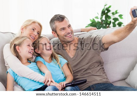 Man taking picture of his children and wife sitting on a couch