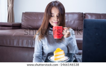Beautiful Asian women sitting in the living room. She holds  mobile phone, Read phone messages, chat, Take a picture of yourself , Concept Technology and daily life.