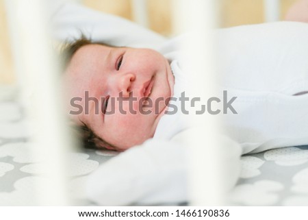 The baby sleeps in the crib. Charming girl sleeps in a bed for sleep, attached to the bed of parents. A small child having a nap in the crib. Baby in the sun nursery