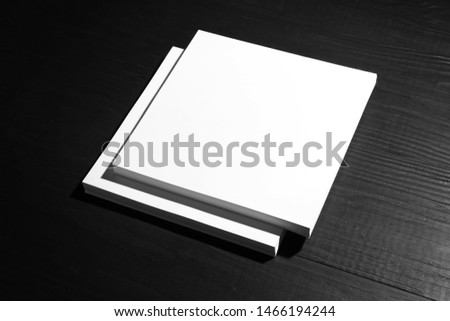Stack of blank paper sheets for brochure on black wooden background. Mock up