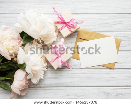 Wedding invitation and envelope with pink peonies on a old white wooden background
