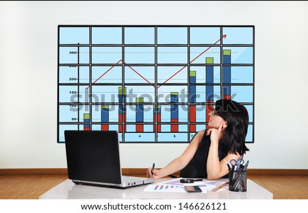 businesswoman in office looking at plasma with chart