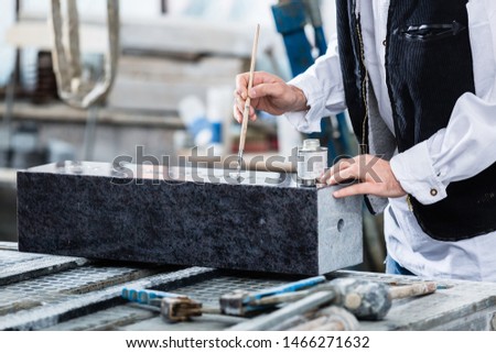 Stonemason painting in engraving with silver paint and brush Royalty-Free Stock Photo #1466271632