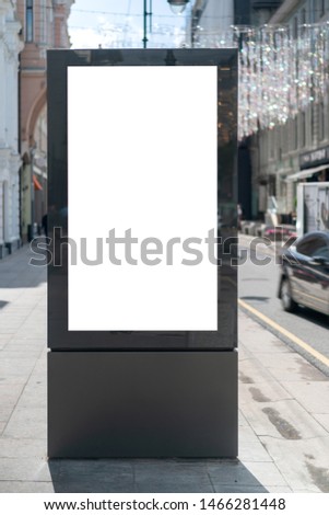 Moc up standard rectangular vertical lightbox on street in city. Advertising construction. Copy space. Lightbox on sidewalk wide street. Against backdrop building and roadway. Royalty-Free Stock Photo #1466281448