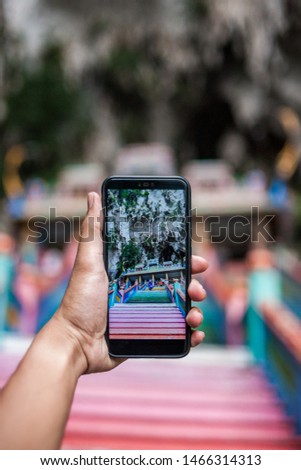 a person take a picture of Batu Caves at stairs.  in the background of Batu Caves, near Kuala Lumpur, Malaysia. Traveling with children concept.