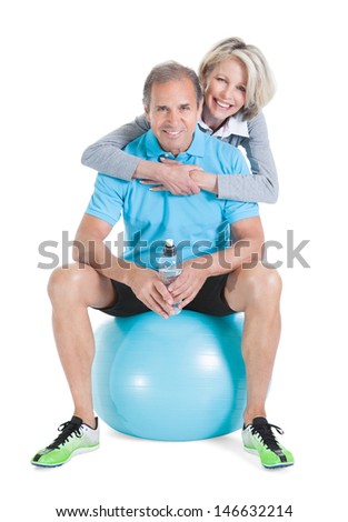 Woman Embracing Mature Man From Behind Sitting On Pilates Ball