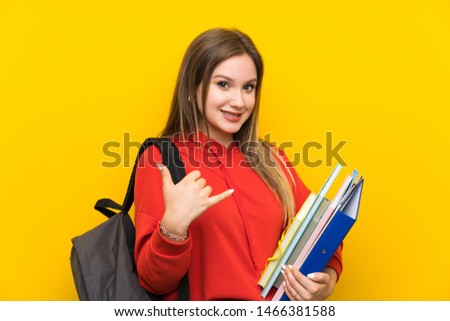 Teenager student girl over yellow background making phone gesture