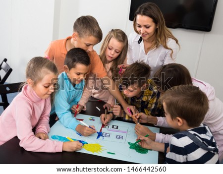 Professor and elementary age  american children drawing together one picture