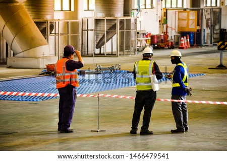 Worker stretching the red white warning tape to the pole at construction site.Red and white Hazardous restricted area tape at construction area of factory to mark territory works. Royalty-Free Stock Photo #1466479541