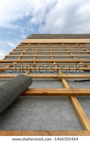 Concept of building new wood or wooden house. Vertical photo of unfinished wooden roof top with special waterproof bitumen membrane of new modern home under construction