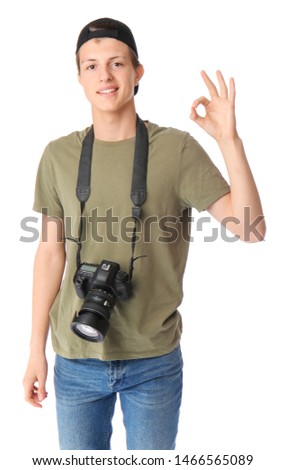 Teenage boy with photo camera showing OK on white background