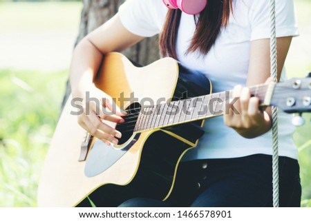 Beautiful young woman with Acustic guitar at nature background