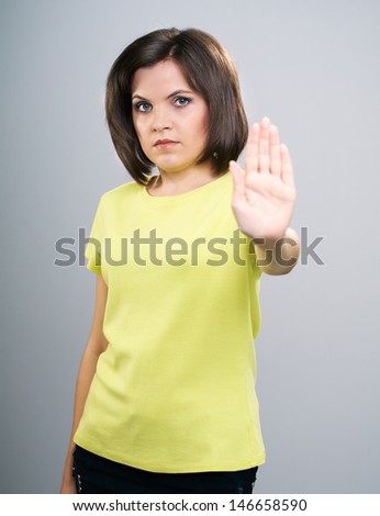 Attractive young woman in a yellow shirt. Shows the stop sign. Isolated on a gray background