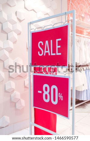 Season sale, black friday and shopping concept. Sale sign on red stand with 80 percent discount price in store shop. Clothes hangers on background