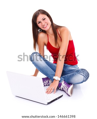 Picture of a happy friendly young woman sitting on the floor behind a laptop. Isolated. 