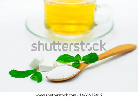 Stevia leaf and Stevia powder in a wooden spoon with Stevia tea in a glass cup