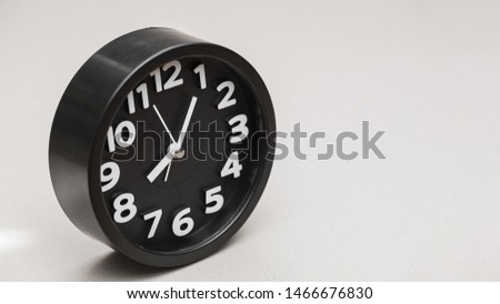 Circular black alarm clock against gray background