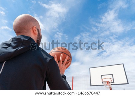 Attractive man playing basketball and dunking basketball in hoop on basketball court.