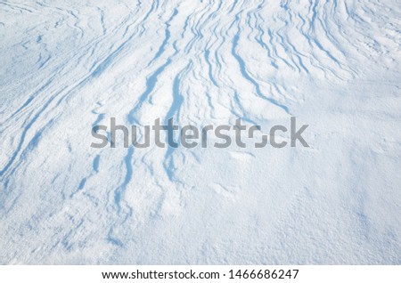Abstract natural winter background texture, white snow surface with curved blue shadows
