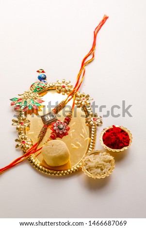 Indian festival Raksha Bandhan , Rakhi with rice grains, kumkum and sweets on plate 