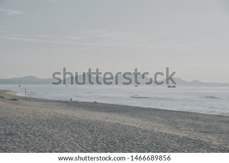 Calm vibe by the seashore at a random beach, with a distant view of faded landscape.
