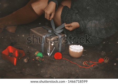 Christmas gift wrap. The woman's hands packing a Christmas gift box on dark background.