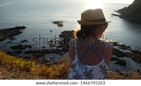 Happy woman enjoying the sunset by the cliff overlooking the ocean 