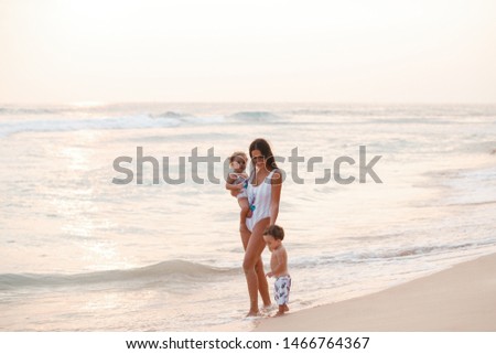 Stylish young mother with kids, family look, swimsuits with pineapple. Family on summer vacation 