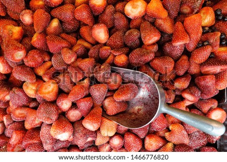 Frozen strawberries with spatula to pick. Red background