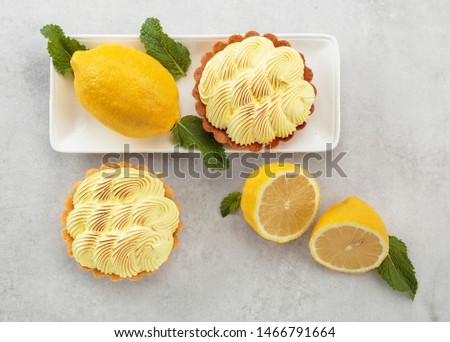 Tartlets with lemon cream and mint on a white marble table. Top view.