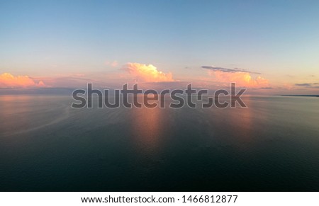 Aerial drone panoramic view of sunset colorful clouds and reflection in water surface of Lake Ontario. Tranquility, calmness, serenity concept. 