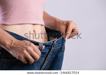 Young slim woman in oversized blue jeans. Fit woman wearing too large pants. Healthcare and woman diet lifestyle concept to reduce belly and shape up healthy stomach muscle. Royalty-Free Stock Photo #1466817014