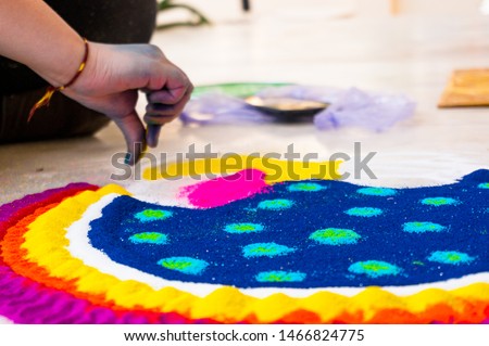 Hand of young indian girl making rangoli from colored powder on diwali eve. These beautiful designs are made in every hindu home to decorate and celebrate the coming of the festivals of diwali Royalty-Free Stock Photo #1466824775