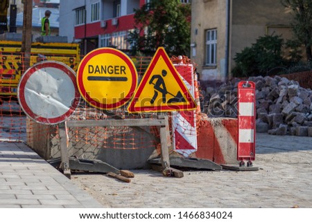 Road signs: stop for dangers, including traffic accidents, natural disasters or other obstructions; roadworks; road closed to all traffic. Against the backdrop of building, street repair in old town.
